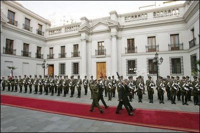 President George W. Bush walks with President Ricardo Lagos of Chile past a unit of Carabineros at the La Moneda Presidential Palace upon arrival for a meeting and private dinner in Santiago, Chile, Nov. 21, 2004. 