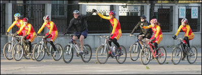 President George W. Bush raises the hand of a cyclist for China's Mountain Biking Team Sunday after completing a ride with the squad during his visit to Beijing.