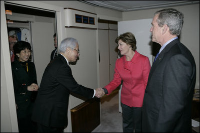 As President Bush looks on, Mrs. Laura Bush shakes hands with Japanese Ambassador to the United States Ryozo Kato and his wife, Hanayo, as the couple greeted the President and First Lady upon their arrival Tuesday, Nov. 15, 2005, to Osaka International Airport.