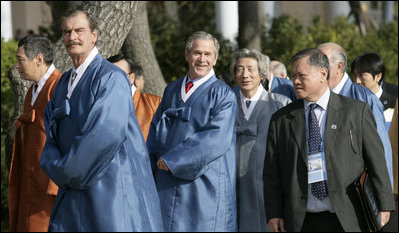 President George W. Bush peaks out behind Mexico President Vincente Fox, left, with Japan's Prime Minister Junichiro Koizumi as APEC leaders walk to the official photograph site Saturday, Nov. 19, 2005, at the Nurimaru APEC House in Busan, Korea.