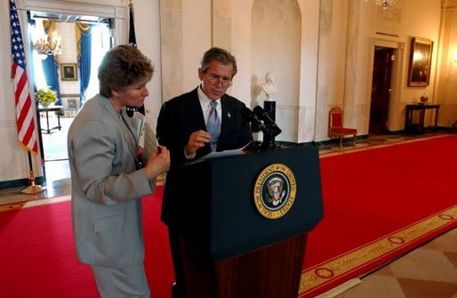 President George W. Bush discusses a speech with Karen Hughes in the Cross Hall of the White House June 6, 2002. White House photo by Eric Draper.