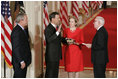 El Presidente George W. Bush observa el jueves, 29 de septiembre de 2005 en el East Room de la Casa Blanca en Washington mientras el Juez John G. Roberts toma el cargo de Presidente de la Corte Suprema ante el Juez de la Corte Suprema John Paul Stevens. La esposa del Juez Roberts, Jane, sostiene La Biblia.