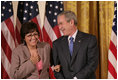 El Presidente George W. Bush está parado de lado de María Hines de Albuquerque, Nuevo México, quien fue galardonada con el Volunteer Service Award el viernes, 7 de octubre de 2005 en el East Room de la Casa Blanca, donde el Presidente Bush honró a seis personas con el premio presidencial al servicio voluntario como parte de la celebración del Mes de la Hispanidad.