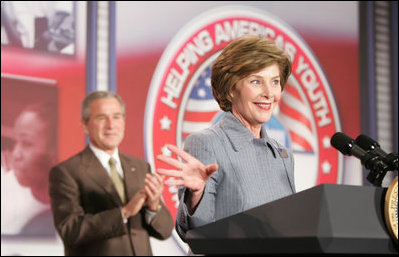 El Presidente George W. Bush, atrás, aplaude mientras la señora Bush hace declaraciones de bienvenida el jueves, 27 de octubre de 2005 en Howard University en Washington, durante la Conferencia de la Casa Blanca para Ayudar a los Niños y Jóvenes de los Estados Unidos.