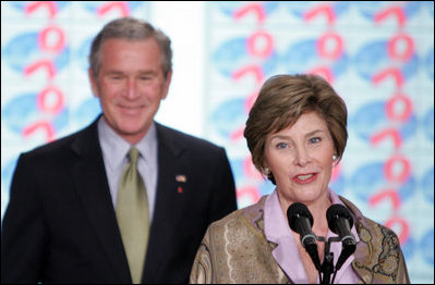 President George W. Bush stands by as he listens to remarks by Mrs. Bush on World AIDS Day before being introduced to the audience at the Dwight D. Eisenhower Executive Office Building Thursday, Dec. 1, 2005.