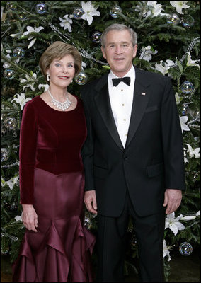 President George W. Bush and Laura Bush stand before the White House Christmas tree in the Blue Room of the White House. In keeping with this year's theme, "All Things Bright and Beautiful!" the Fraser fir is decorated with fresh white lilies.