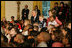 President George W. Bush and Laura Bush sit with children, Monday, Dec. 5, 2005 at the White House, as they watch a dance performance during the White House Children's Holiday Reception in the East Room.