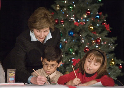 Laura Bush writes a note on a child's letter to his parent who is serving overseas, as she visits with children at the Naval and Marine Corps Reserve Center in Gulfport, Miss., Monday, Dec. 12, 2005, showing them a White House holiday video featuring the Bush's dogs "Barney and Miss Beazley."