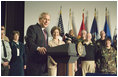 With Mrs. Laura Bush looking on, President George W. Bush addresses military medical caregivers Wednesday, Dec. 21, 2005, before visiting with the wounded at the National Naval Medical Center in Bethesda, Md. The President told the caregivers, "... On behalf of a grateful nation, thanks for doing your duty, thanks for serving, thanks for being an important part of this march for freedom; and thanks, most of all, for bringing comfort and aid and solace to those who have been hurt on the battlefield and their families."