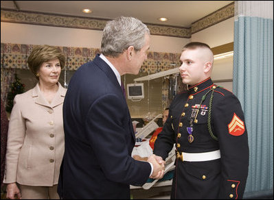 President George W. Bush shakes the hand of Marine Cpl. Andrew L. Tinsley of Annapolis, Md., Wednesday, Dec. 21, 2005, after Cpl Tinsley was presented the Purple Heart during a visit by the President and Laura Bush to the National Naval Medical Center in Bethesda, Md.