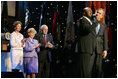 President George W. Bush puts his arm around Singer Bebe Winans as he sings 'God Bless America' during the 'Saluting Those Who Serve' event at the MCI Center in Washington, D.C., Tuesday, Jan. 18, 2005. Also pictured are, from left, Laura Bush, Lynne Cheney, and Vice President Dick Cheney.