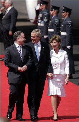 President George W. Bush and Laura Bush walk with Scotland's First Minister Jack McConnell during the playing of national anthems upon their arrival at Glasgow's Prestiwick Airport, July 6, 2005.