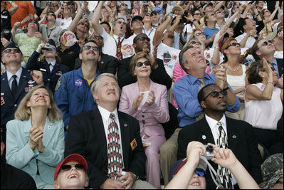 Laura Bush applauds as she folllows the launch of the Space Shuttle Discovery, Tuesday, July 26, 2005, at the Kennedy Space Center in Cape Canaveral, Florida. Mrs. Bush is joined by Florida Governor Jeb Bush, right, and NASA Astronaut Scott Altman, left.