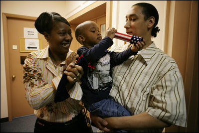 Kevion Thigpen, 3, held by his parents Kanyatta "Ken" Thigpen and his girlfriend Jewell Reed plays with a kaleidescope given to him by Laura Bush during a visit to the Rosalie Manor Community and Family Services center in Milwaukee, Wis., Tuesday, March 8, 2005. Citing a New York Times article by Jason DeParle Mrs. Bush credits Mr. Thigpen's determination to be a responsible father with bringing her attention to the needs of boys and young men.