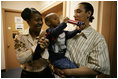 Kevion Thigpen, 3, held by his parents Kanyatta "Ken" Thigpen and his girlfriend Jewell Reed plays with a kaleidescope given to him by Laura Bush during a visit to the Rosalie Manor Community and Family Services center in Milwaukee, Wis., Tuesday, March 8, 2005. Citing a New York Times article by Jason DeParle Mrs. Bush credits Mr. Thigpen's determination to be a responsible father with bringing her attention to the needs of boys and young men.