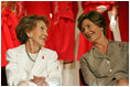 Laura Bush and former First Lady Nancy Reagan share a moment Thursday, May 12, 2005, at the John F. Kennedy Center for the Performing Arts during the unveiling of The Heart Truth’s First Ladies Red Dress Collection.