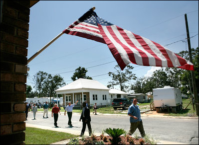 President George W. Bush waves as he is joined by Biloxi Mayor A.J. Holloway, left, Monday, Aug. 28, 2006, during President Bush's walking tour in the same Biloxi, Miss., neighborhood he visited following Hurricane Katrina in September 2005. The tour allowed President Bush the opportunity to assess the progress of the area's recovery and rebuilding efforts following the devastating hurricane.