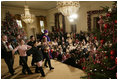 President George W. Bush and Mrs. Laura Bush sit with children of deployed U.S. military personnel and watch a performance of "Willy Wonka" by members of The Kennedy Center Education Department in the East Room Monday, Dec. 4, 2006.