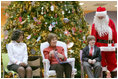 Mrs. Laura Bush sits with patient escorts Allison Meads, left, and Matthew Morgan, as she reads to an audience of children, patients and hospital staff Friday, Dec. 8, 2006, at The Children's National Medical Center in Washington, D.C., where Mrs. Bush visited with patients and debuted the 2006 Barney Cam video.