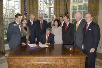 Accompanied by Laura Bush and legislators, President George W. Bush signs H.R. 3402, The Violence Against Women and Department of Justice Reauthorization Act of 2005, during a ceremony in the Oval Office Thursday, Jan. 5, 2005. The bill is a comprehensive package that reauthorizes Department of Justice programs to combat domestic violence, dating violence, sexual assault, and stalking.