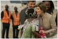 Mrs. Laura Bush embraces 11-year-old Jamila Ahmed after she presented flowers to Mrs. Bush, Tuesday, Jan. 17, 2006, upon her arrival to Abuja, Nigeria. Deputy Chief of U.S. Mission Thomas Fuery and Nigeria's Minister of Education Chinwe Obaji, are seen in the background.