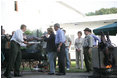 As President George W. Bush and Laura Bush look on, German Chancellor Angela Markel slices up some barbeque Thursday, July 13, 2006, during dinner in Trinwillershagen, Germany. The Bushes continue their Europe trip when they depart Germany Friday en route to Russia and the G8 Summit.