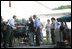 As President George W. Bush and Laura Bush look on, German Chancellor Angela Markel slices up some barbeque Thursday, July 13, 2006, during dinner in Trinwillershagen, Germany. The Bushes continue their Europe trip when they depart Germany Friday en route to Russia and the G8 Summit.