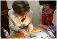 Mrs. Laura Bush receives instruction in arts and crafts Monday, July 17, 2006, during an exhibit at the Baltic Star Hotel on the grounds of the Konstantinovsky Palace Complex in Strelna, Russia, site of the G8 Summit that ended Monday.