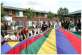 Mrs. Laura Bush joins the children and staff of the Meadowbrook Collaborative Community Center in playing with a colorful parachute during her visit to the facility Tuesday, June 6, 2006 in St. Louis Park, Minn.