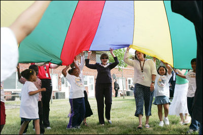 Mrs. Laura Bush participates in playing with a colorful parachute with children and staff outside the Meadowbrook Collaborative Community Center, Tuesday, June 6, 2006 in St. Louis Park. Minn.