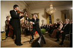 President George W. Bush watches as Japanese Prime Minister Junichiro Koizumi adjusts the microphone for country music entertainer Shoji Tabuchi Thursday evening, June 29, 2006 in the East Room of the White House, during the entertainment following the official dinner in honor of Koizumiís visit to the United States.