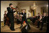 President George W. Bush watches as Japanese Prime Minister Junichiro Koizumi adjusts the microphone for country music entertainer Shoji Tabuchi Thursday evening, June 29, 2006 in the East Room of the White House, during the entertainment following the official dinner in honor of Koizumiís visit to the United States.