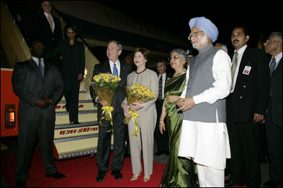 President George W. Bush and Mrs. Bush stand with flowers presented upon their arrival Wednesday, March 1, 2006, at New Delhi's Indira Gandhi International Airport where they were greeted by India's Prime Minister Manmohan Singh, right, and his wife, Gursharan Kaur.