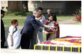 President George W. Bush and Laura Bush sprinkle flowers on the south side of the Mahatma Gandhi Memorial Thursday, March 2, 2006, during a wreath-laying ceremony in Rajghat, India.