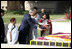 President George W. Bush and Laura Bush sprinkle flowers on the south side of the Mahatma Gandhi Memorial Thursday, March 2, 2006, during a wreath-laying ceremony in Rajghat, India.