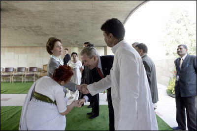 President George W. Bush reaches to shake the hand of Dr. Nirmila Deshpande, as Laura Bush exchanges handshakes with Rajnish Kumar after they were met by the pair Thursday, March 2, 2006 in Rajghat, India for the wreath-laying ceremony at the Mahatma Gandhi Memorial.