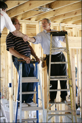 President George W. Bush shakes hands with people helping rebuild Jerry Akins family home, Wednesday, March 8, 2006 in Gautier, Miss., on the site where the Akins home was destroyed by Hurricane Katrina.