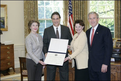 President George W. Bush and Mrs. Bush present the Preserve America award for private preservation to Judy Christa-Cathey, Vice President Brand Management, and Scott Douglas Schrank, Vice President Brand Performance and Support, both of Hampton Hotels' nationwide Save-A-Landmark program, in the Oval Office Monday, May 1, 2006.