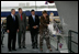 President George W. Bush joins his father, Former President George H. W. Bush and Northrop Grumman President Mike Petters, as his sister Doro Bush Koch breaks the bottle to christen the George H.W. Bush (CVN 77) in Newport News, Virginia, Saturday, Oct. 7, 2006.