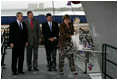 President George W. Bush joins his father, Former President George H. W. Bush and Northrop Grumman President Mike Petters, as his sister Doro Bush Koch breaks the bottle to christen the George H.W. Bush (CVN 77) in Newport News, Virginia, Saturday, Oct. 7, 2006.