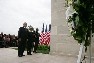 President George W. Bush and Laura Bush, accompanied by Sgt. Timothy Boyd of the Military District of Washington, stand before a memorial wreath Monday, Sept. 11, 2006, during a moment of silence at the Pentagon in Arlington, Va., to commemorate the fifth anniversary of Sept. 11, 2001 attacks.