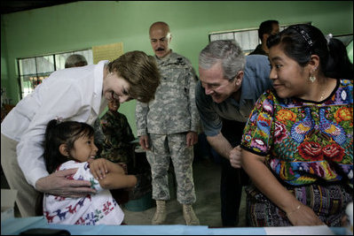 President George W. Bush and Mrs. Laura Bush play with a young girl during a visit Monday, March 12, 2007, to the Carlos Emilio Leonardo School in Santata Cruz Balanya, Guatemala. The couple visited a medical readiness and training exercise site at the school.