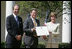 Mrs. Laura Bush presents a plaque to John McLaughlin, center, president and CEO of the USS Midway Museum in San Diego, Calif., and Scott McGaugh, marketing director of the museum, honoring them with a 2007 Preserve America Presidential Award in the Rose Garden at the White House Wednesday, May 9, 2007.