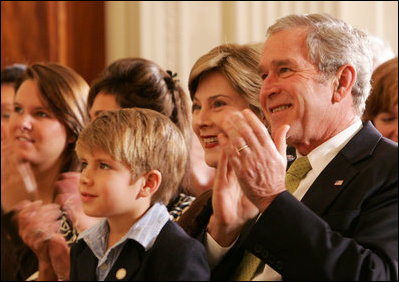 President George W. Bush and Mrs. Laura Bush are joined by Elijah Atkins, Friday, Nov. 16, 2007 in the East Room of the White House, as they listen to Atkins' father, country music star Rodney Atkins, performing for guests during the celebration of National Adoption Day. Rodney Atkins is the 2007-2008 national celebrity spokesperson for The National Council for Adoption.