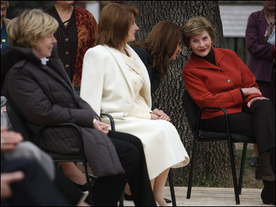 Mrs. Laura Bush leans in to listen to Alexandra Coman, fiance of Romania's Foreign Minister Adrian Cioroianu, as they join other guests, including Mrs. Maria Basescu, in white, spouse of Romania's President Taian Basescu, and Mrs. Jeannie de Hoop Scheffer, spouse of NATO Secretary General Jaap de Hoop Scheffer, at the Dimitrie Gusti Village museum in Bucharest.