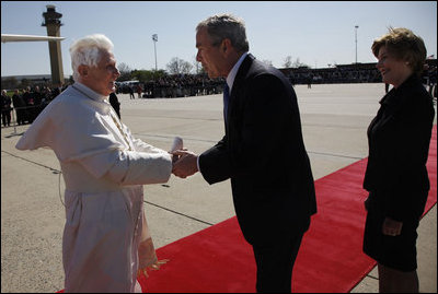 President George W. Bush takes the hand of Pope Benedict XVI as he and Mrs. Laura Bush welcomed the Pope to the United States upon his landing at Andrews Air Force Base, Maryland. Pope Benedict will visit the White House Wednesday and celebrate Mass Thursday before continuing on to New York City.