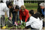 Mrs. Laura Bush helps children plant flowers at the First Bloom Event, Monday, April 21, 2008, during her visit to celebrate National Park week at the Castle Clinton National Monument in New York City.