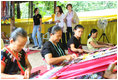 Mrs. Laura Bush and daughter Ms. Barbara Bush try on shawls created by weavers carrying on the traditional Karen ethnic craft at the Mae La Refugee Camp at Mae Sot, Thailand. In her August 7, 2008 comments, Mrs. Bush pointed out that the weavings are done to help generate money for the refugees and can be purchased via the Internet through consortiums that work with women at the camp. The camp houses at least 39,000 refugees waiting for a safe time to return to their home country. Many have decided the wait of 20 years has been too long and have immigrated to the United States and other countries.