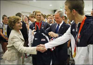 President George W. Bush looks at the U.S. Olympic jacket presented to him as Mrs. Laura Bush shakes hands with U.S. Olympic gold medalist Michael Phelps Sunday, Aug. 10, 2008, at the National Aquatics Center in Beijing.