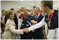 President George W. Bush looks at the U.S. Olympic jacket presented to him as Mrs. Laura Bush shakes hands with U.S. Olympic gold medalist Michael Phelps Sunday, Aug. 10, 2008, at the National Aquatics Center in Beijing.